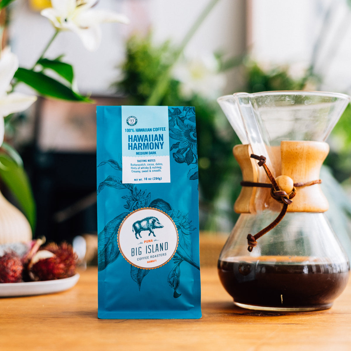 Hawaiian Harmony coffee package with a Chemex coffee maker on a wooden table.